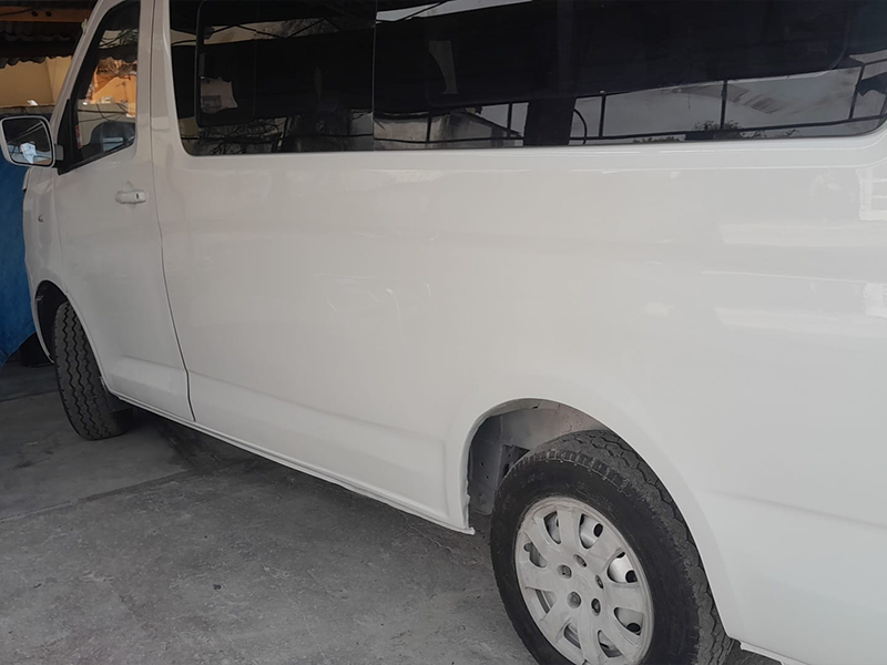 White bus with the left side middle panel fully repaired, smoothed, and repainted.