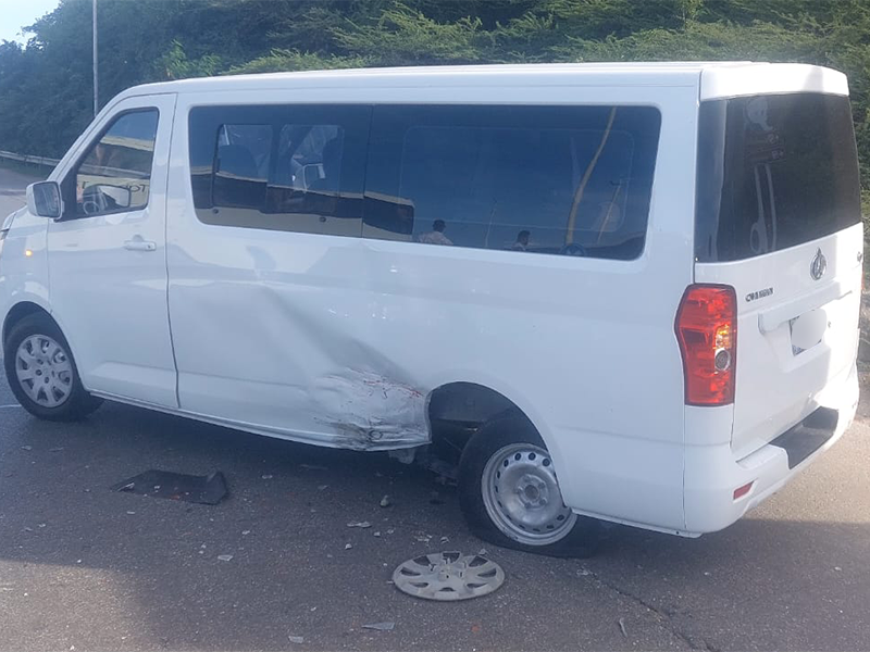 White commercial bus with mid-section collision damage on the left side panel.