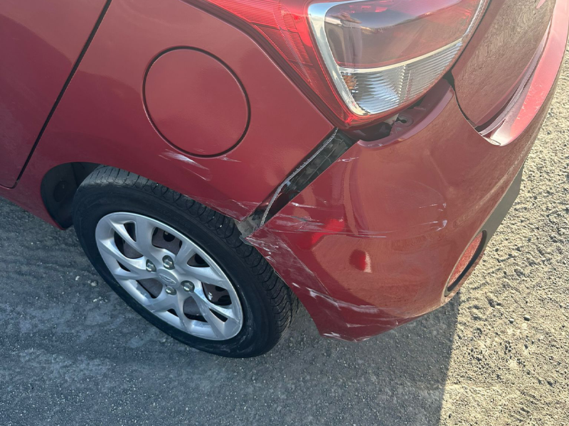 Red Hyundai i10 with severe collision damage on the rear left quarter panel.