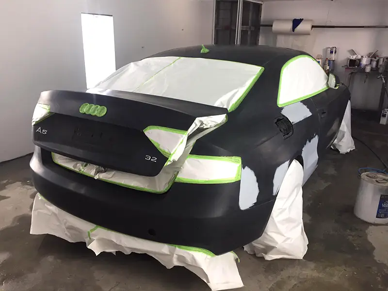 Black Audi with small surface dents and scratched paint before professional refinishing