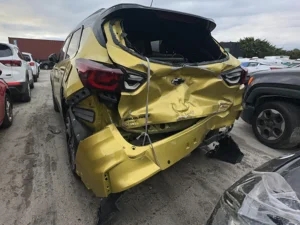 Chevrolet Gold-Lime with severe, crushed rear-end collision damage including crumpled trunk, bumper, and frame rail impacts.