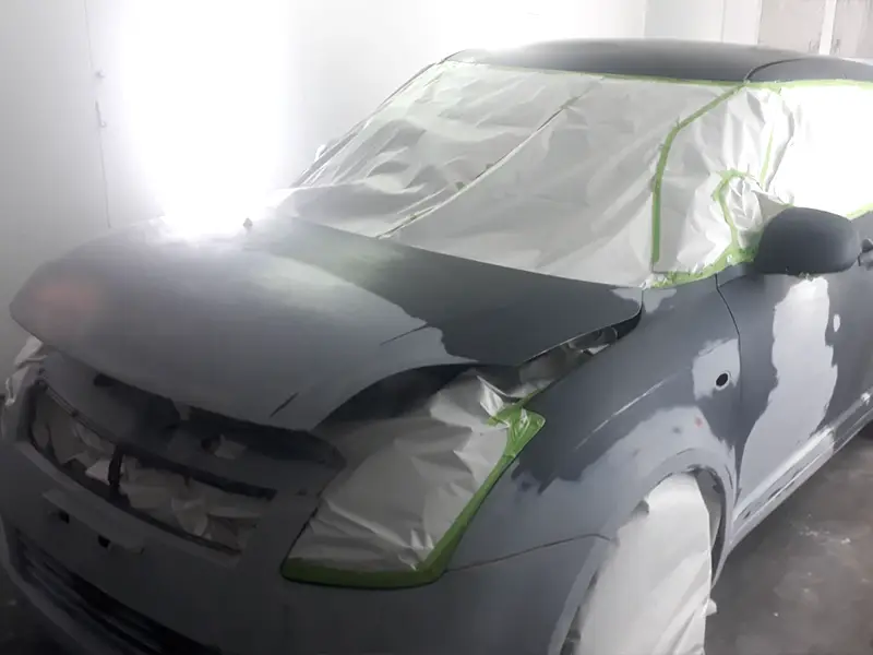 Suzuki Swift in the shop undergoing dent repair and surface preparation for a full repaint.