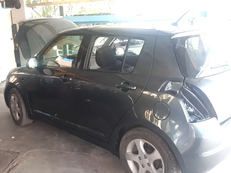 Fully repainted gray Suzuki Swift with a flawless gloss finish after dent repair.