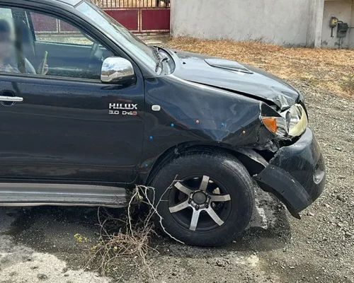 Black Toyota Hilux with significant body damage and dents before repair